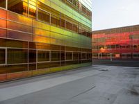 an orange yellow and green building next to each other on top of a road under a clear blue sky