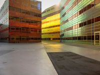 an orange yellow and green building next to each other on top of a road under a clear blue sky