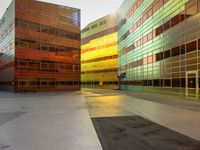 an orange yellow and green building next to each other on top of a road under a clear blue sky