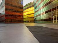 an orange yellow and green building next to each other on top of a road under a clear blue sky