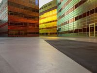 an orange yellow and green building next to each other on top of a road under a clear blue sky