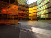 an orange yellow and green building next to each other on top of a road under a clear blue sky