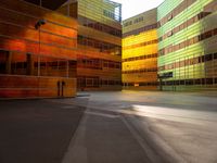 an orange yellow and green building next to each other on top of a road under a clear blue sky