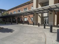 a building with a covered entrance and large windows that overlook it in front of the building