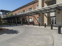 a building with a covered entrance and large windows that overlook it in front of the building