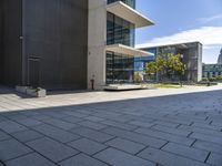 an empty sidewalk next to a very large building with glass windows on the sides of each building