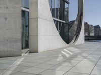 large silver building with rounded windowed concrete facade on side street in london, england