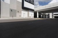 a large gray building with black trim and a parking lot outside, some cars parked in the street