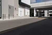 a large gray building with black trim and a parking lot outside, some cars parked in the street