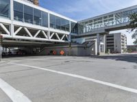 the large building has many windows and is near an elevated ramp over the street with traffic cones