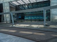 a large glass building next to the road on a sunny day with sun streaming through the roof