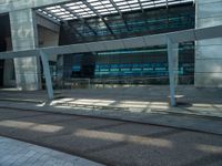 a large glass building next to the road on a sunny day with sun streaming through the roof