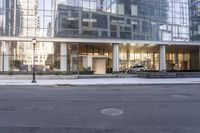 the front entrance of a glass and stone office building in a city with a car parked in front