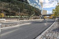 a bus drives by a large building on a busy road with cobblestones around it