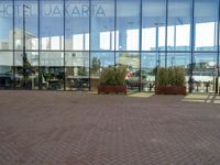 a large building with several potted trees outside the windows of it next to a couple of benches