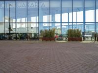 a large building with several potted trees outside the windows of it next to a couple of benches