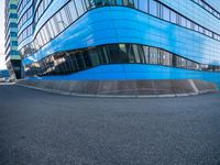 an intersection view of an office building and it's reflection on the pavement while someone is standing next to it