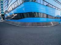 an intersection view of an office building and it's reflection on the pavement while someone is standing next to it