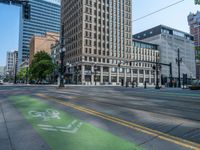 the green paint is painted on a bike path in front of an office building and large, trees