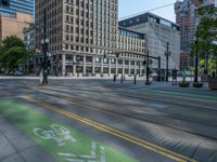 the green paint is painted on a bike path in front of an office building and large, trees