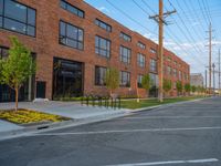 an empty street in front of a large red brick building on the other side of the road is a street light that has a line for motorists