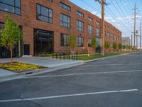 an empty street in front of a large red brick building on the other side of the road is a street light that has a line for motorists