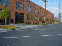 an empty street in front of a large red brick building on the other side of the road is a street light that has a line for motorists