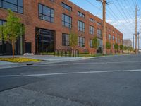 an empty street in front of a large red brick building on the other side of the road is a street light that has a line for motorists