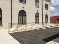 a metal railing leading to the parking lot in front of a building with windows on either side