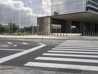 a building with an interesting metal roof sits in the middle of a cross walk in front of it