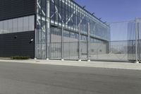 a black building with metal fence near an empty parking lot of concrete streets and street lights