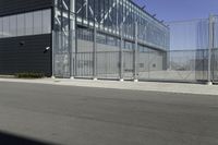 a black building with metal fence near an empty parking lot of concrete streets and street lights