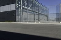 a black building with metal fence near an empty parking lot of concrete streets and street lights