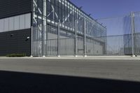 a black building with metal fence near an empty parking lot of concrete streets and street lights