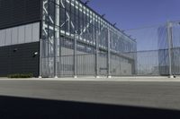 a black building with metal fence near an empty parking lot of concrete streets and street lights