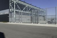 a black building with metal fence near an empty parking lot of concrete streets and street lights