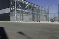 a black building with metal fence near an empty parking lot of concrete streets and street lights