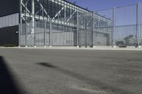 a black building with metal fence near an empty parking lot of concrete streets and street lights