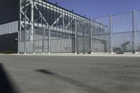 a black building with metal fence near an empty parking lot of concrete streets and street lights