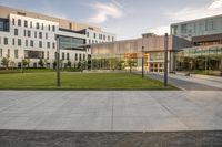 a city street surrounded by grass and tall buildings at the end of a street there is a paved pathway in front of the building