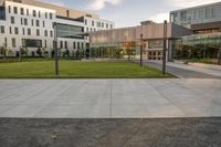 a city street surrounded by grass and tall buildings at the end of a street there is a paved pathway in front of the building