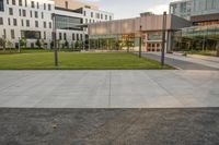 a city street surrounded by grass and tall buildings at the end of a street there is a paved pathway in front of the building