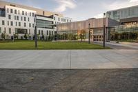 a city street surrounded by grass and tall buildings at the end of a street there is a paved pathway in front of the building