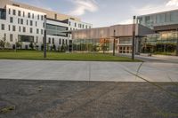 a city street surrounded by grass and tall buildings at the end of a street there is a paved pathway in front of the building