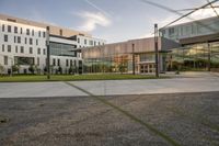 a city street surrounded by grass and tall buildings at the end of a street there is a paved pathway in front of the building