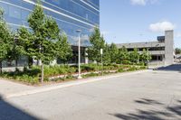 a paved parking lot with trees and shrubs near a building's entrance that has been renovated