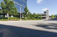 a paved parking lot with trees and shrubs near a building's entrance that has been renovated