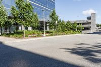 a paved parking lot with trees and shrubs near a building's entrance that has been renovated