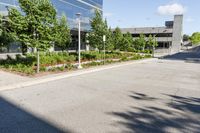 a paved parking lot with trees and shrubs near a building's entrance that has been renovated