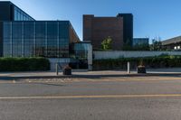 a white building with lots of windows near a street and a bench and fenced off area